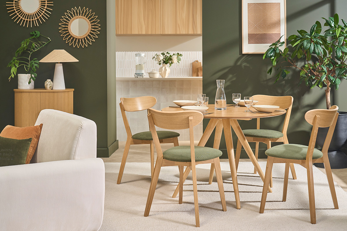 Sillas vintage de madera clara de roble y tela verde caqui alrededor de una mesa en un comedor moderno.