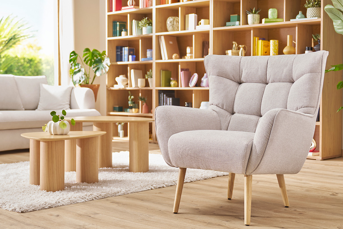Sill�n escandinavo AVERY en tejido beige, base de madera, en un interior luminoso.