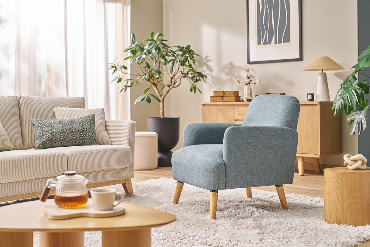 Sill�n escandinavo de tela con patas de madera clara, ubicado en un sal�n moderno.