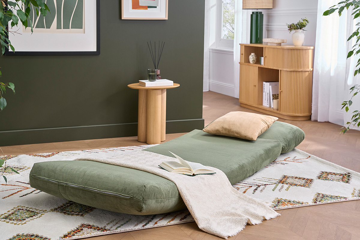 Sill�n SPENCER de pana verde kaki desplegado como cama, sobre una alfombra, con coj�n beige.