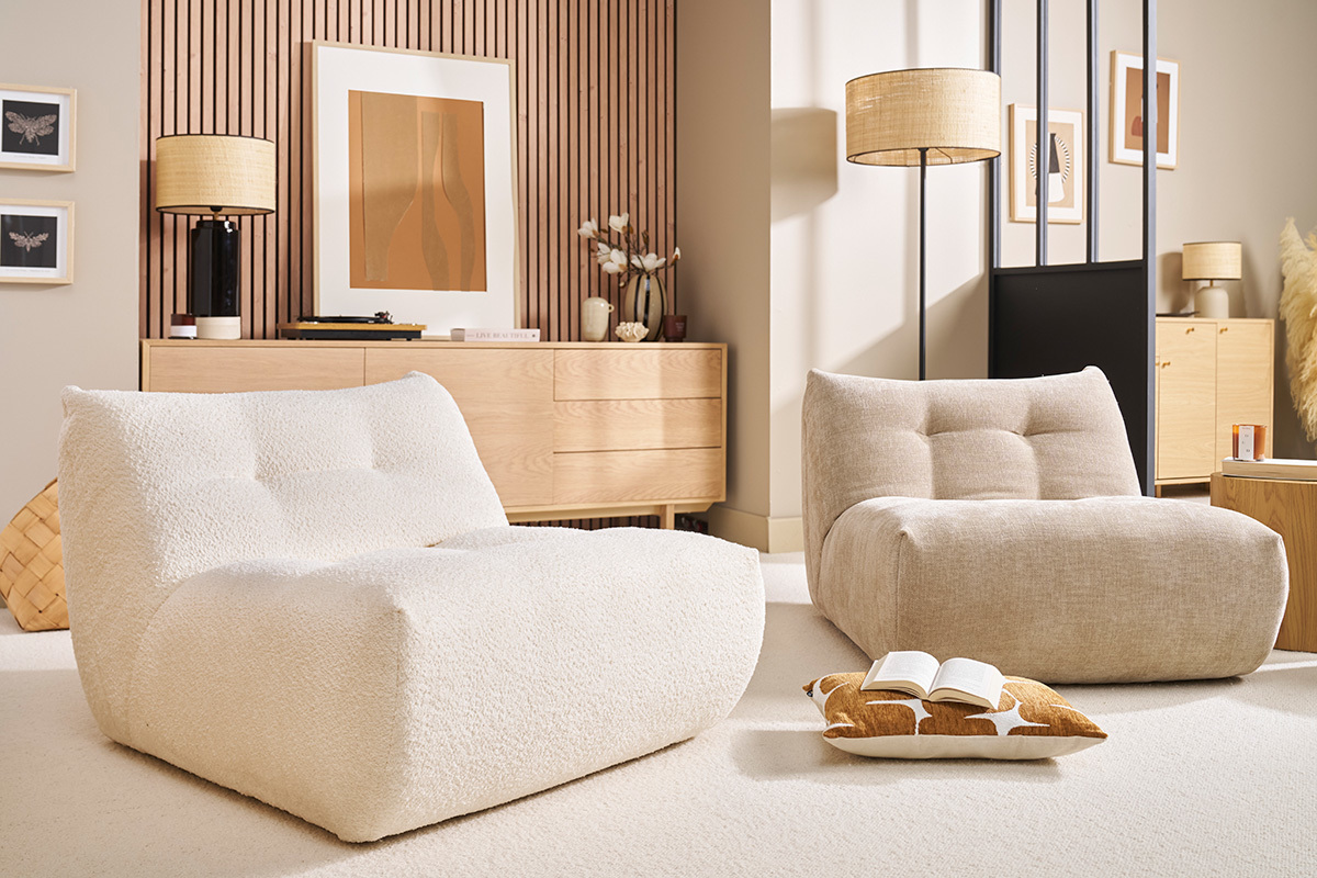 Dos sillones lounge de tela clara en una sala de estar moderna, vista lateral.