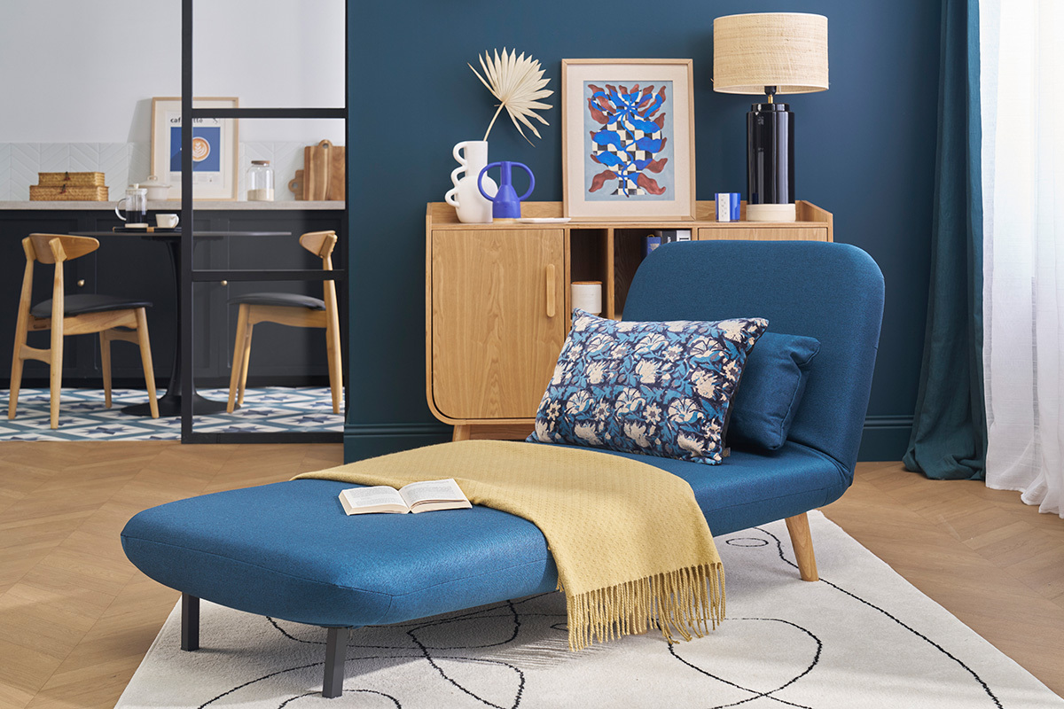 Sill�n convertible AMIKO azul oscuro sobre fondo de decoraci�n escandinava, vista lateral.