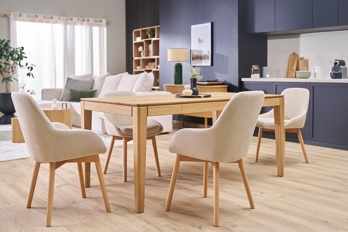 Sillas escandinavas de tela beige y madera clara alrededor de una mesa de madera.