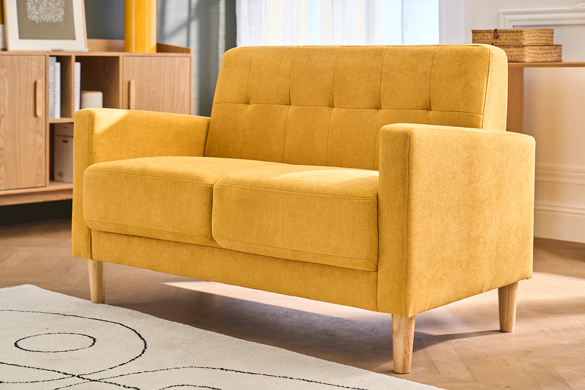 Sof� escandinavo de 2 plazas amarillo mostaza, pata de madera, vista de �ngulo en un sal�n moderno.