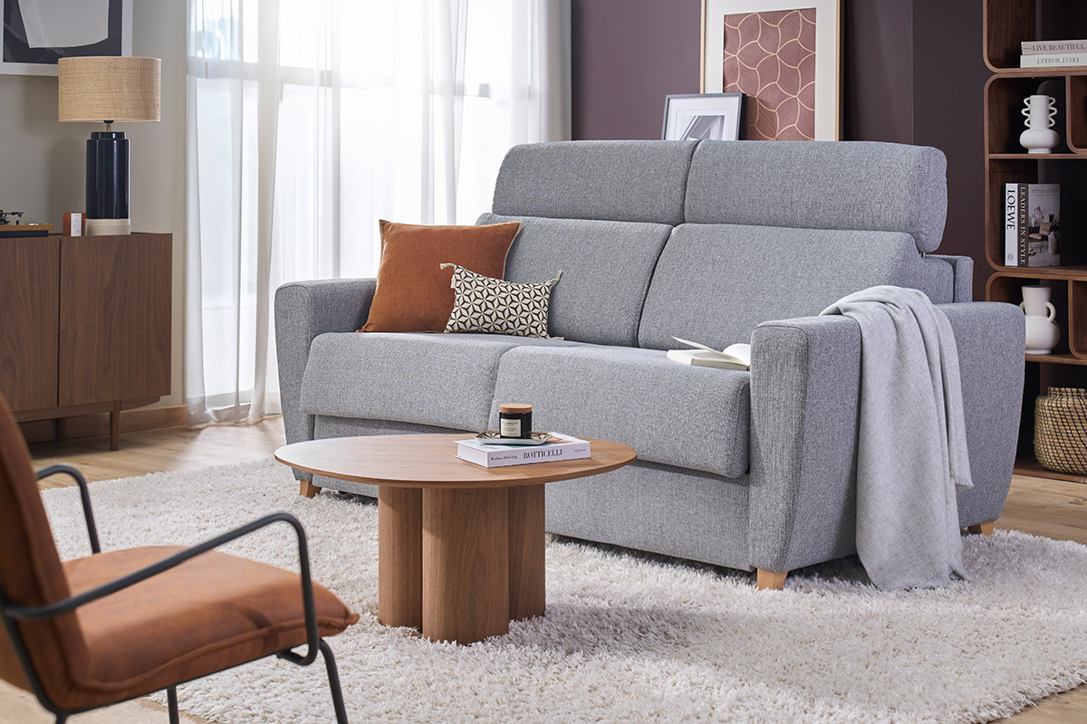 Sof� convertible de 3 plazas GOYA en tejido gris con reposacabezas ajustables, vista en tres cuartos en un sal�n moderno.