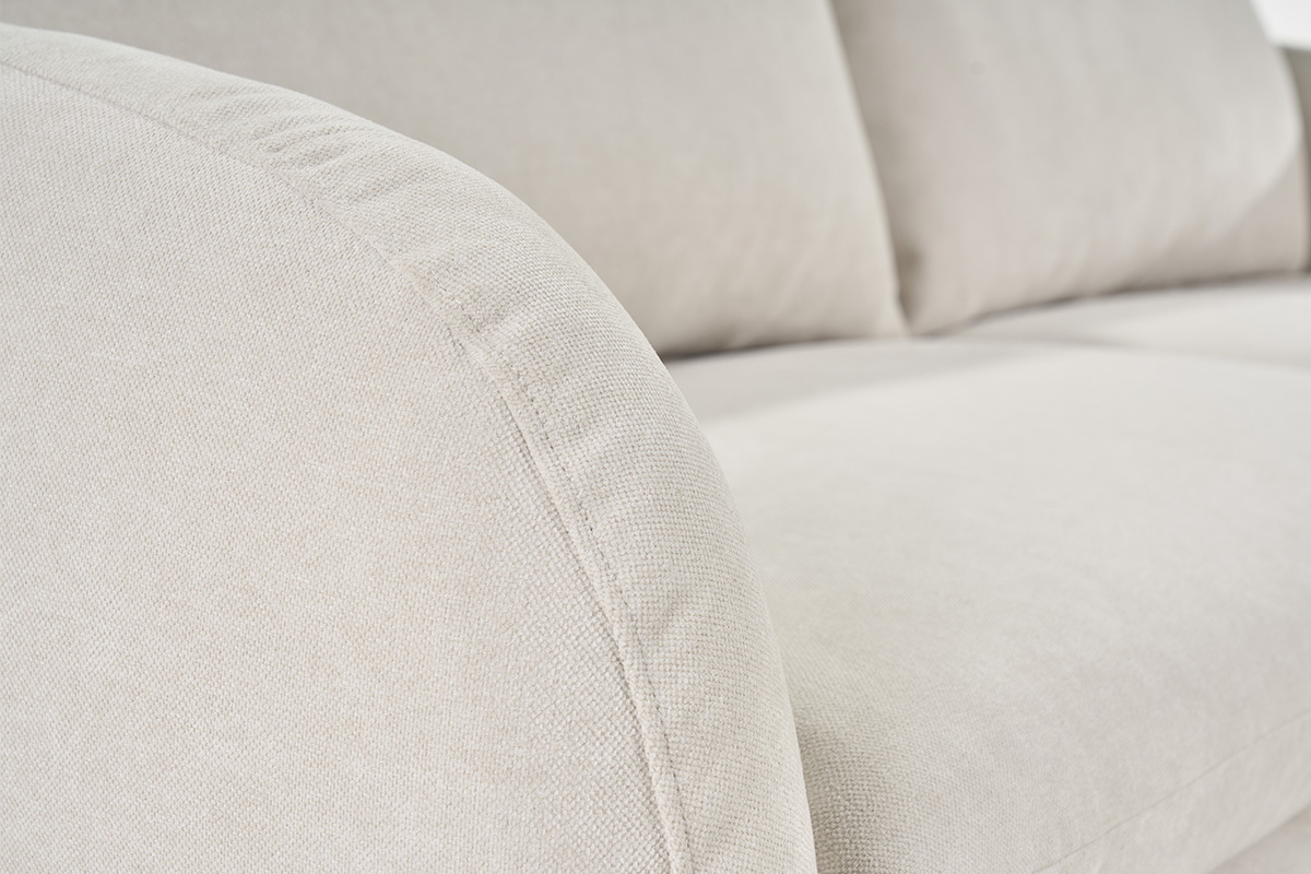 Primer plano del sof� de tela efecto terciopelo beige, con reposabrazos redondeado.