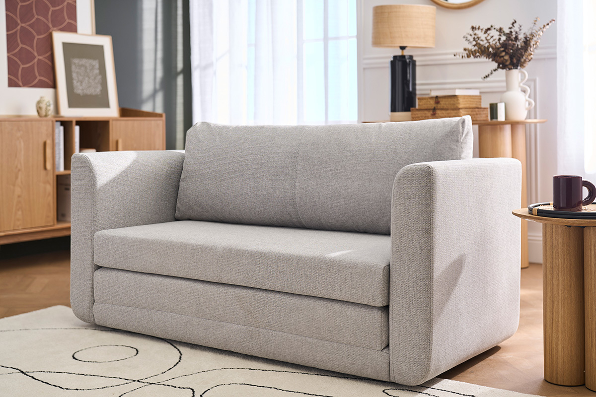 Sof� convertible de 2 plazas en tela gris claro, vista frontal, en un sal�n moderno.