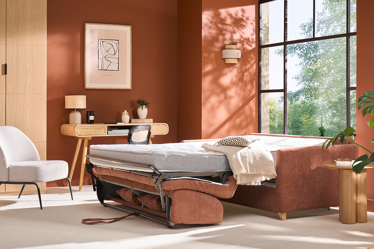 Sof cama convertible de 3 plazas en tela terracota desplegado como cama con colchn, vista lateral.