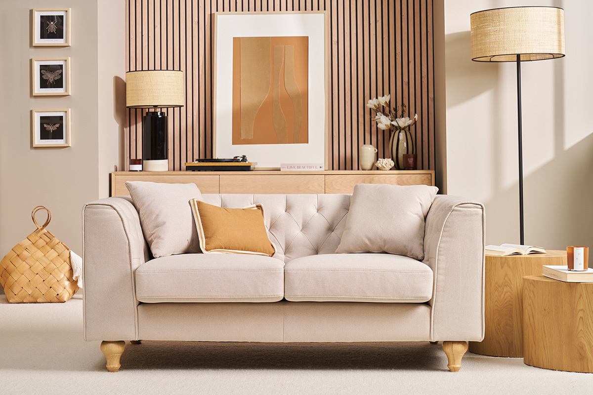 Sof de 2 plazas tapizado beige con cojines, vista frontal.