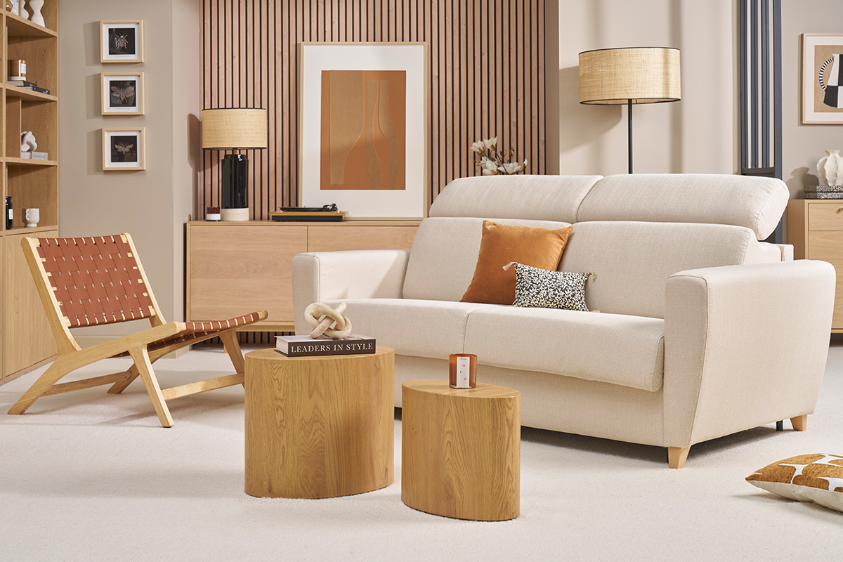 Sof cama beige GOYA con reposacabezas ajustables, vista frontal, en una sala con muebles de madera clara.