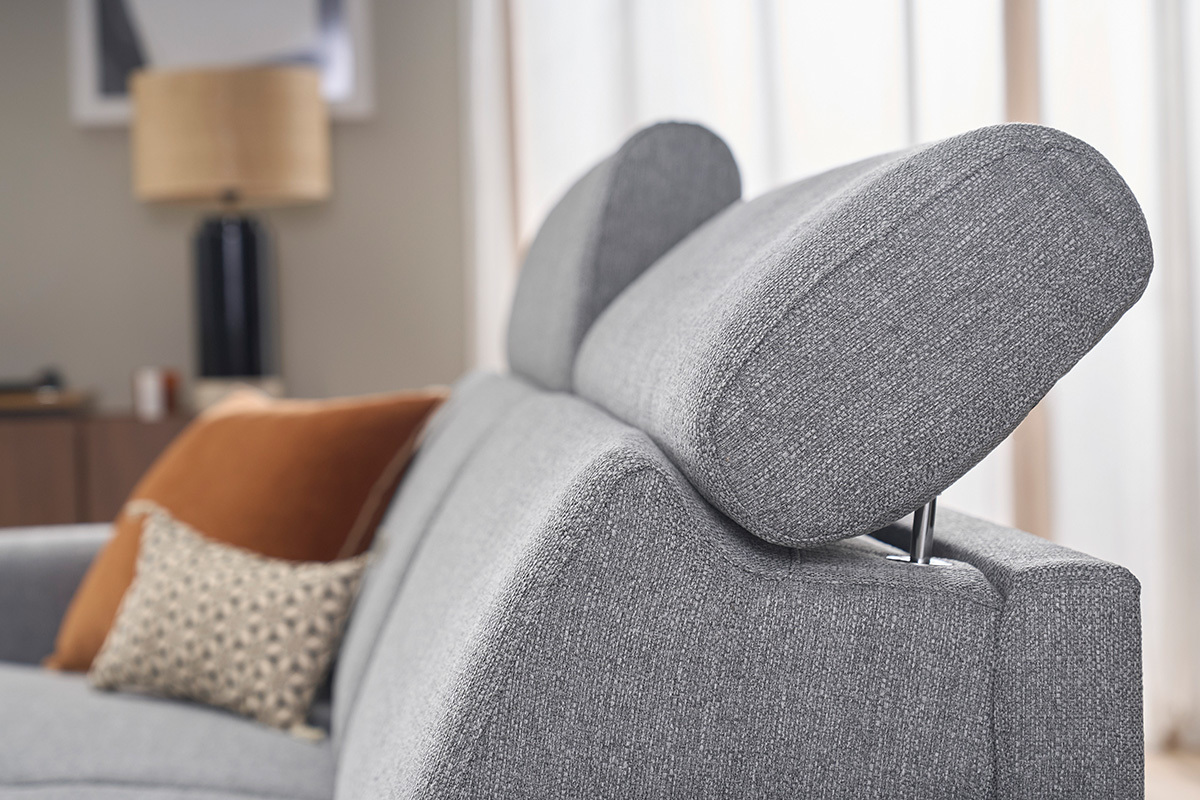 Detalle de los reposacabezas ajustables de un sof� cama gris claro, con cojines decorativos.