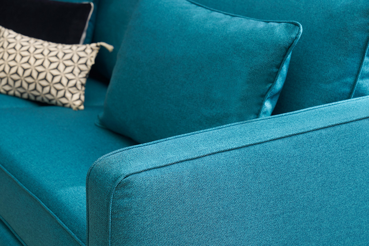 Sof� escandinavo azul petr�leo con cojines geom�tricos, vista cercana.