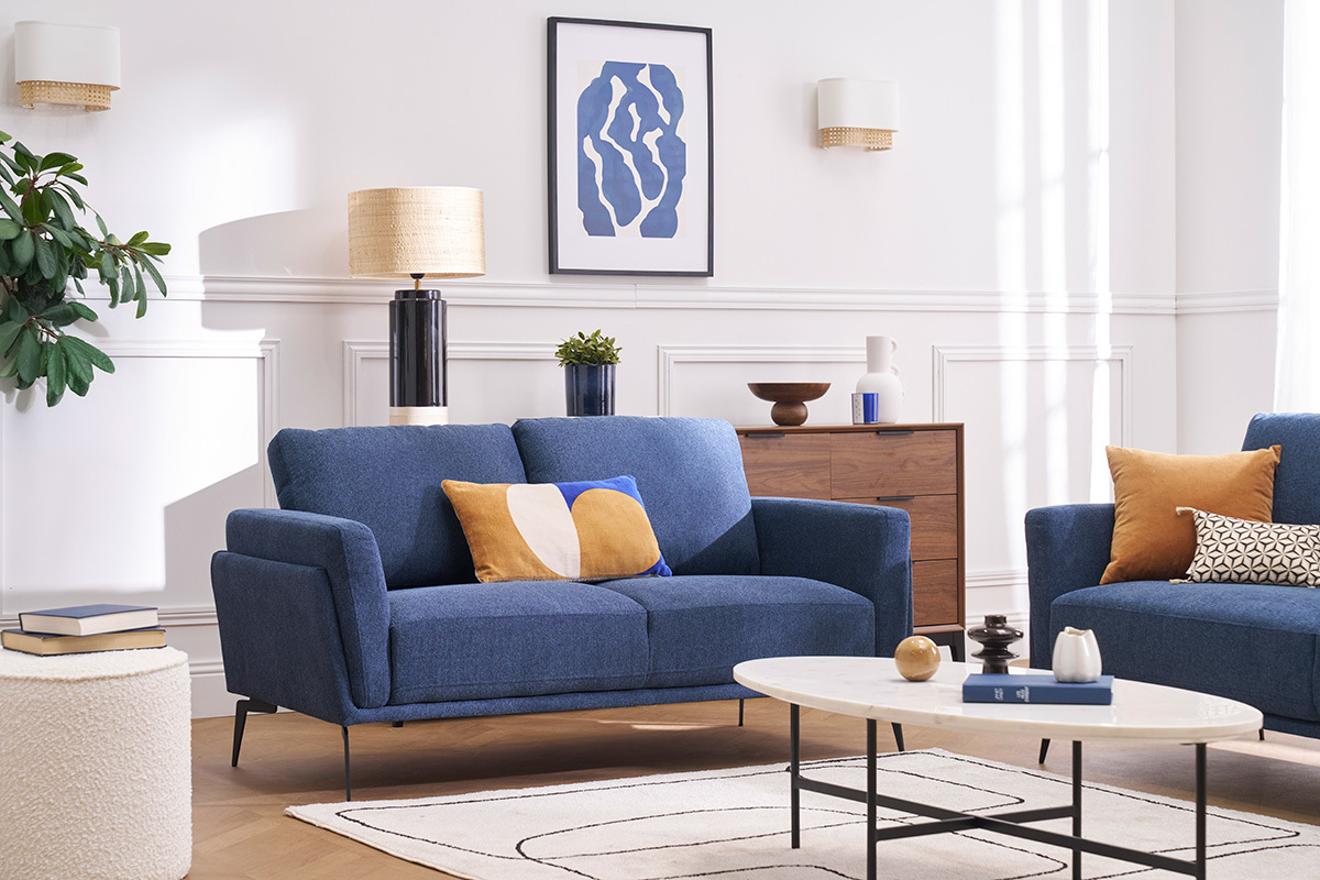 Sof� de dise�o de 2 plazas en tejido azul en un sal�n luminoso con mesa de centro y decoraci�n moderna.
