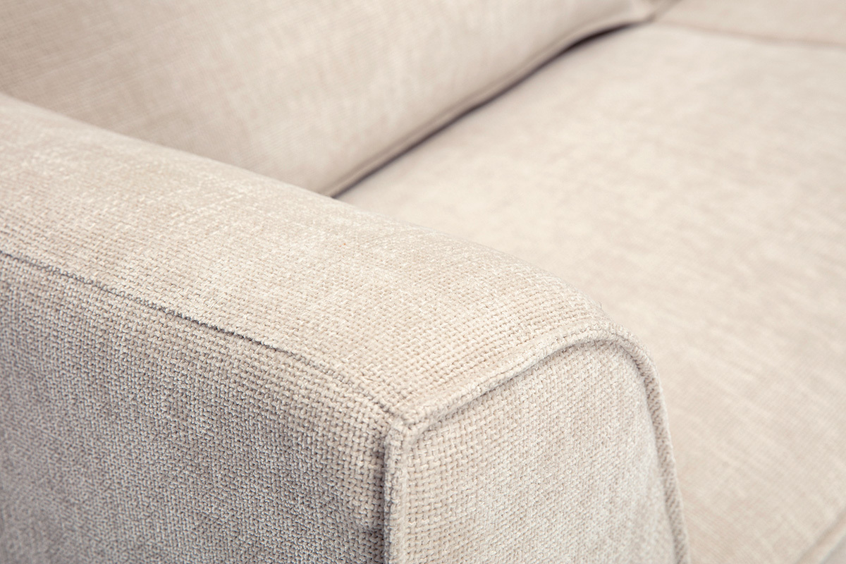 Detalle de un sof� de dise�o de 3 plazas en tejido efecto terciopelo texturizado beige, vista de cerca del reposabrazos.