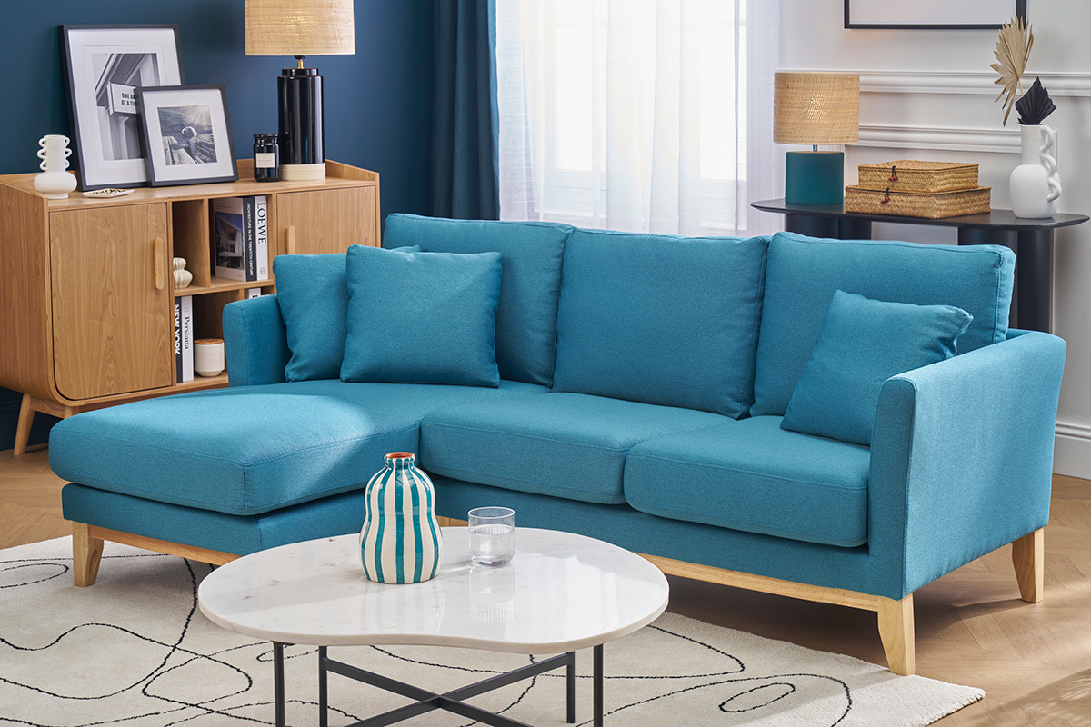 Sof� esquinero izquierdo azul petr�leo y madera clara, en un sal�n con mesa baja y buffet de madera.