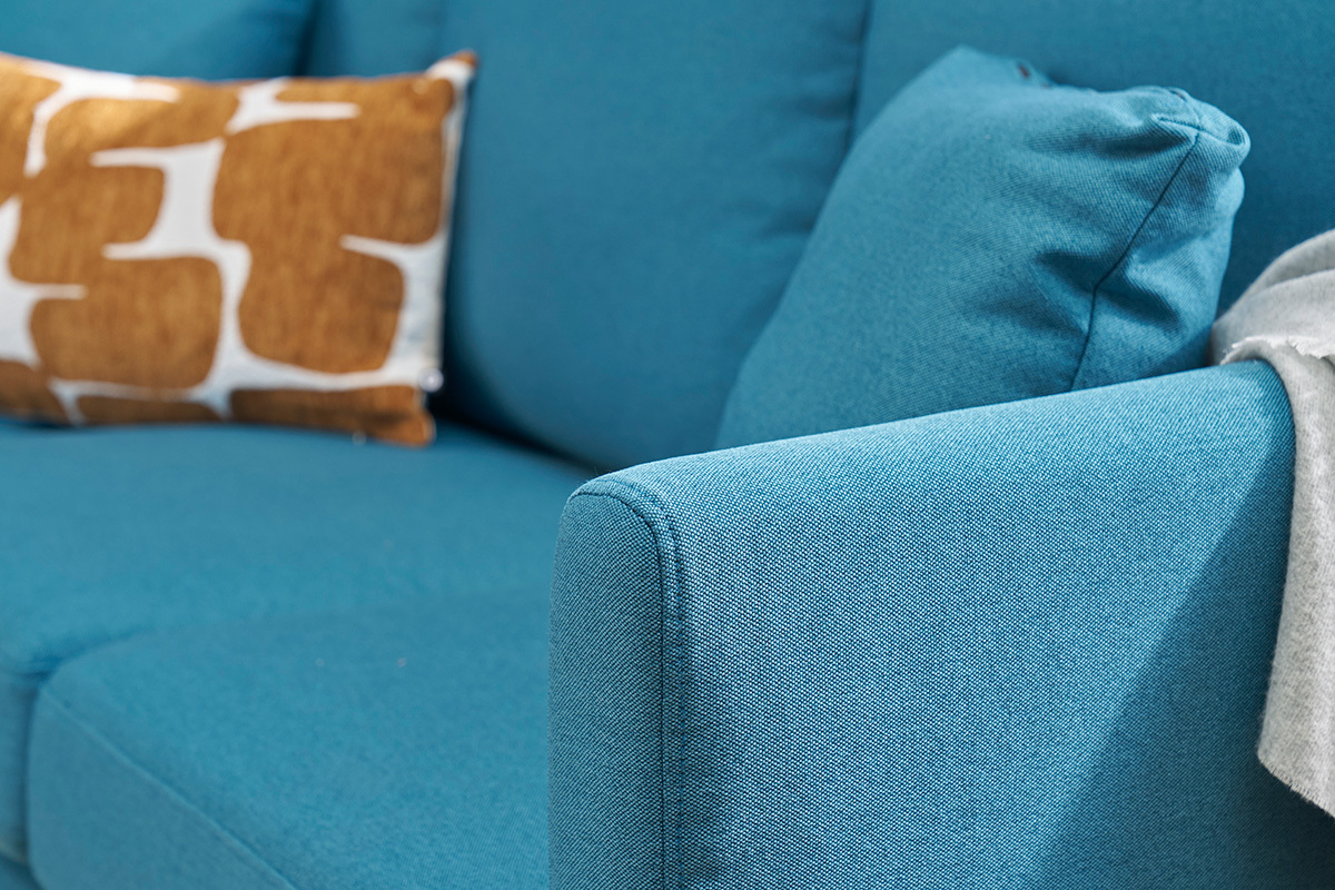 Primer plano de un sof� esquinero azul petr�leo con cojines.