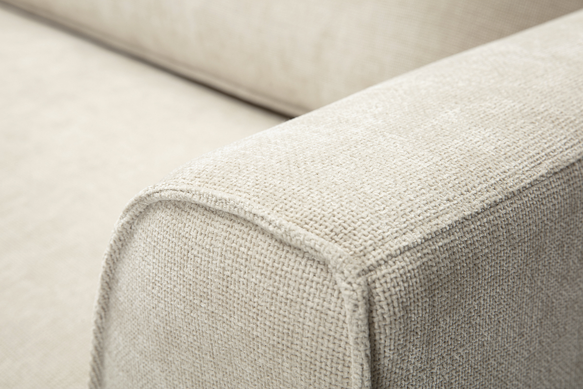 Primer plano del reposabrazos de un sof� de tela con efecto terciopelo texturizado beige.