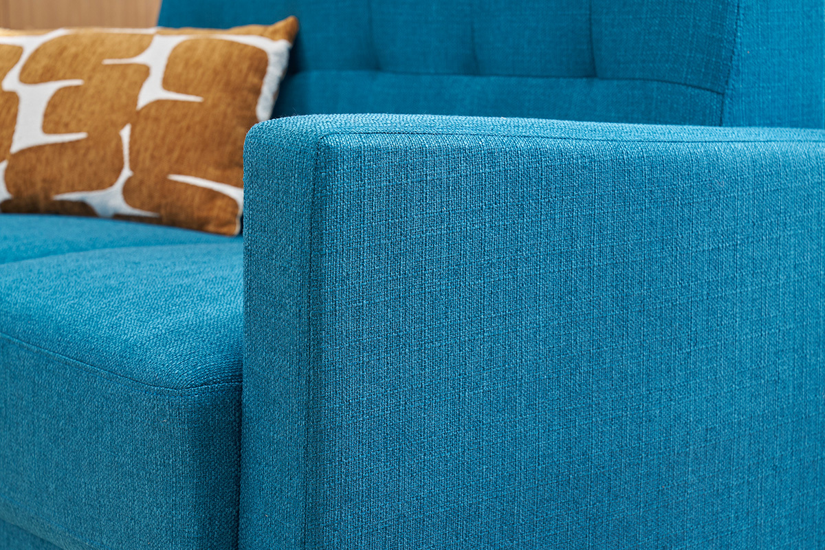 Sof� escandinavo azul petr�leo con coj�n, vista lateral cercana.