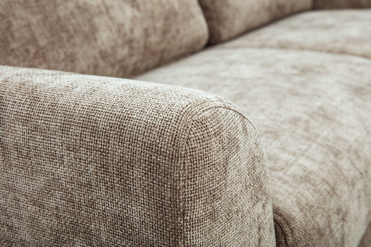 Primer plano del apoyabrazos de un sof� de 3 plazas de tela efecto terciopelo texturizado en color topo.