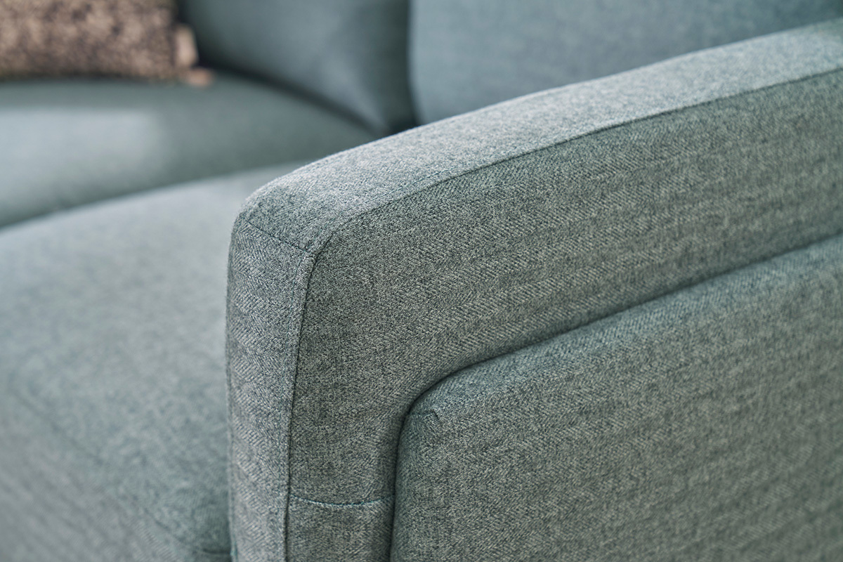 Apoyabrazos de un sof� de dise�o de 2 plazas en verde gris�ceo.
