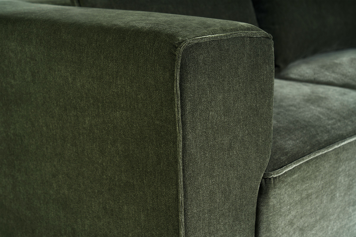 Detalle del sof� modular de 5 plazas en tejido con efecto terciopelo verde caqui, vista de cerca de un reposabrazos.