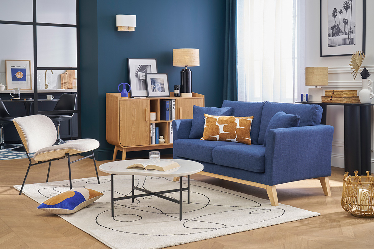 Sal�n con sof� escandinavo de tela azul oscuro y patas de madera, mesa baja y mueble de madera clara.