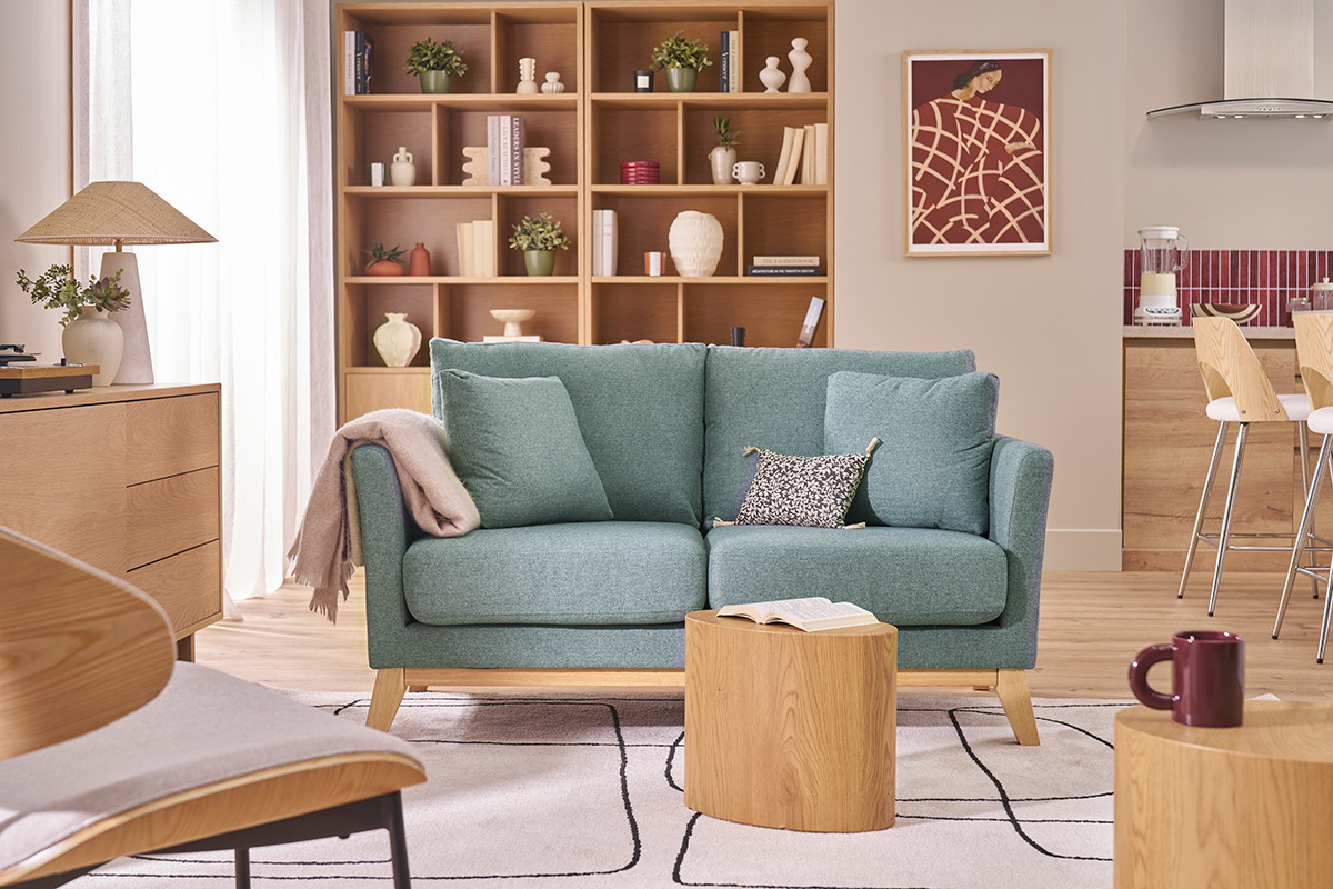 Sof� de 2 plazas en tela verde gris�ceo y madera clara con cojines, vista frontal en una sala de estar.