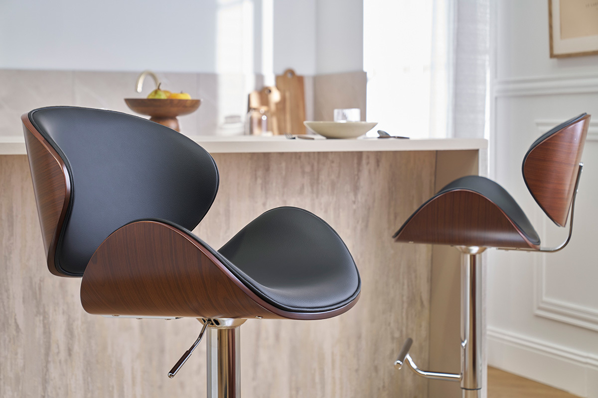 Dos taburetes de bar negros, madera oscura y metal cromado, frente a un mostrador de cocina.