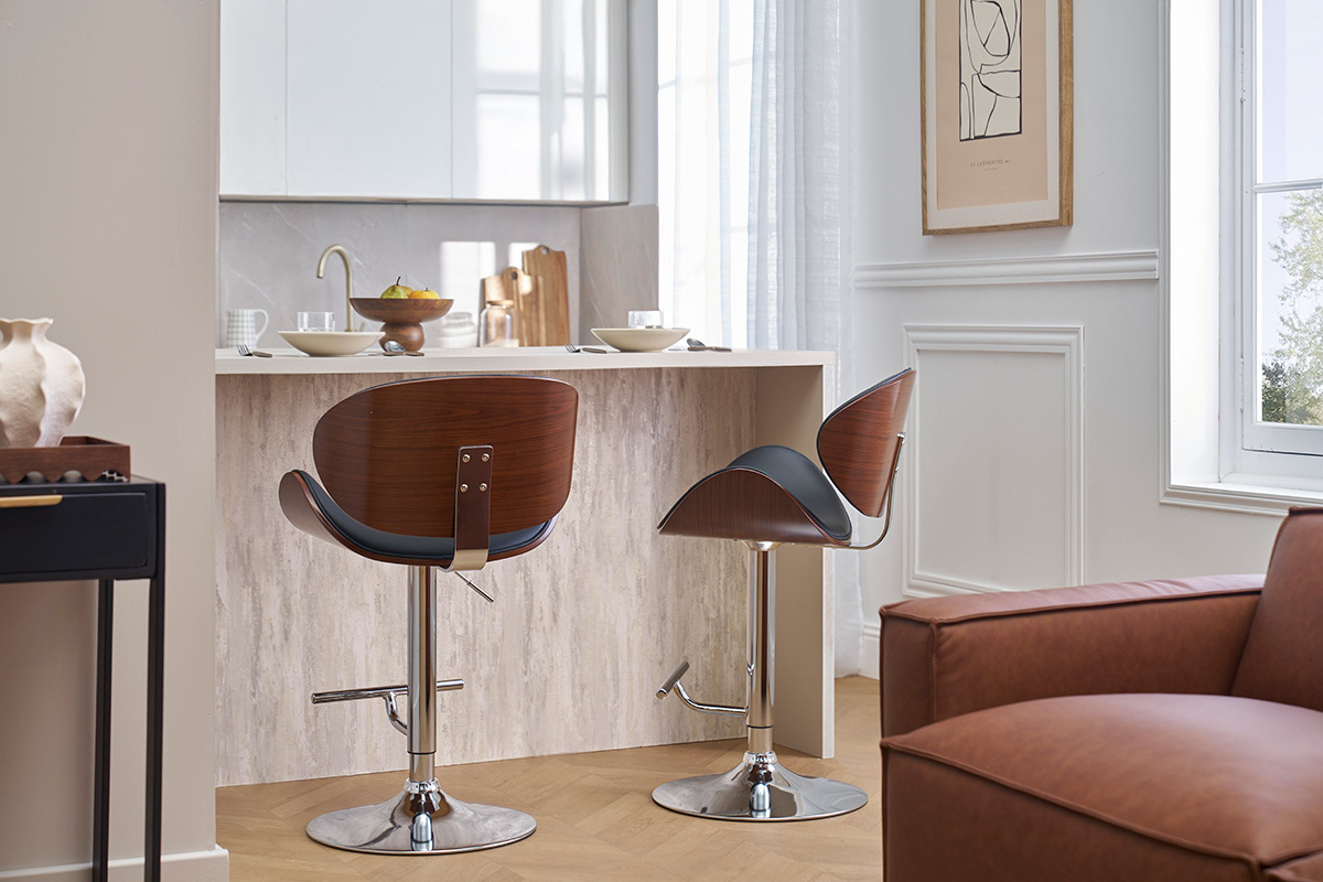 Dos taburetes de bar negros y de madera oscura frente a un mostrador, vista trasera.