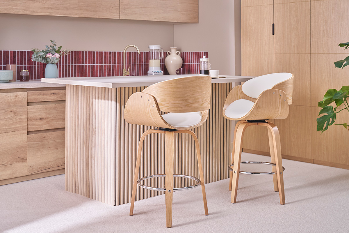 Dos taburetes de bar giratorios blancos y de madera clara frente a una isla de cocina.
