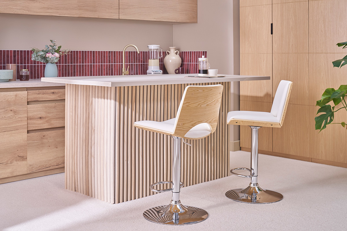 Taburetes de bar ajustables blancos y de madera clara PANACH en una cocina moderna con isla central.