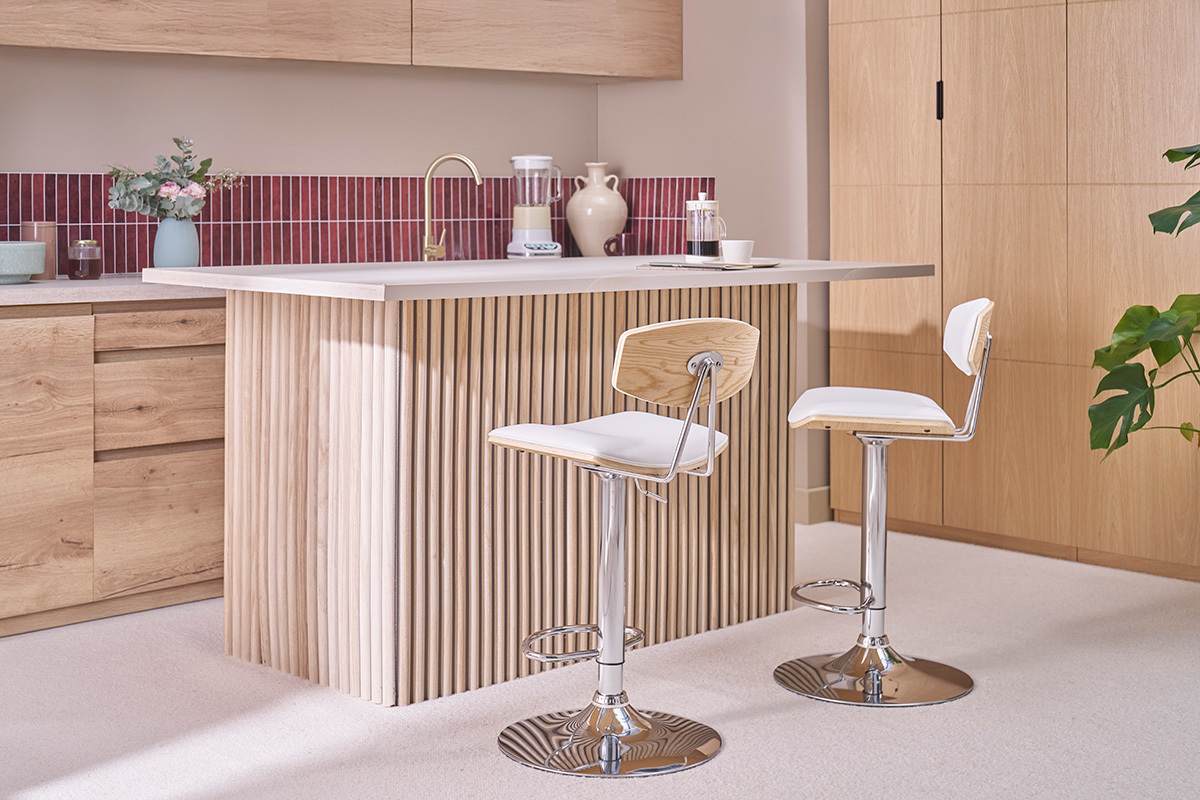 Dos taburetes de bar blancos y de madera clara frente a una isla de cocina de madera.