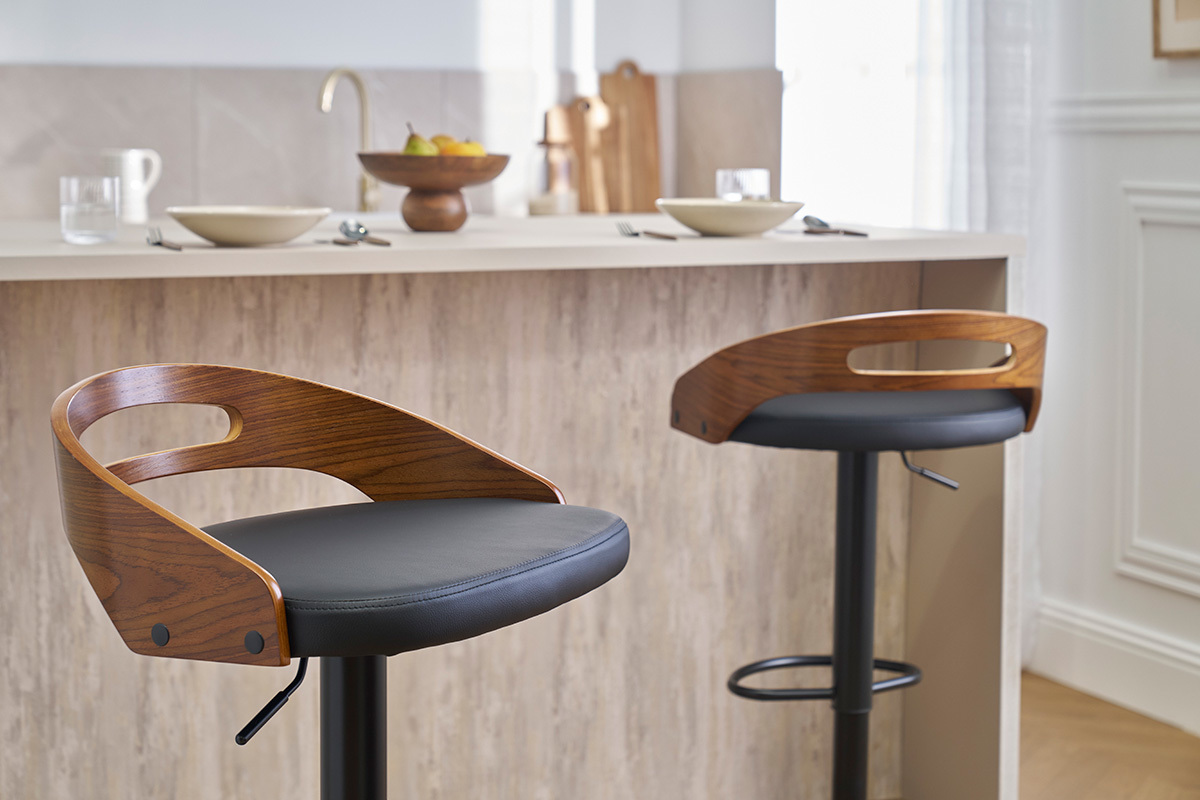 Dos taburetes de bar MANO de madera de nogal y cuero negro frente a una encimera de cocina.