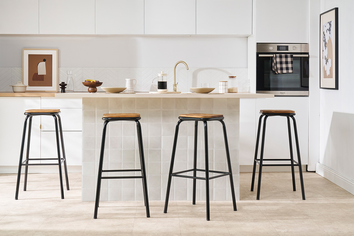 Taburetes MEMPHIS negros y madera oscura frente a una isla de cocina.