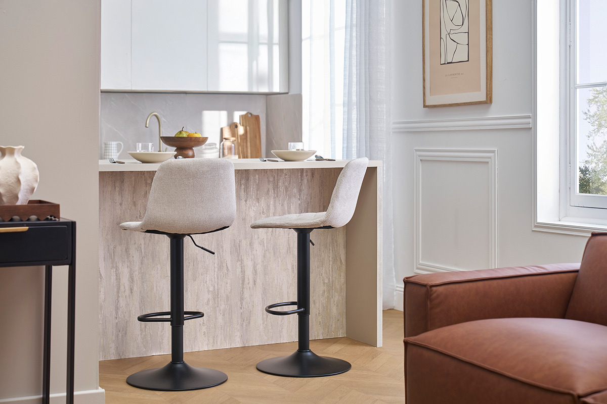 Dos taburetes de bar ajustables en beige y negro, de perfil, frente a un mostrador.