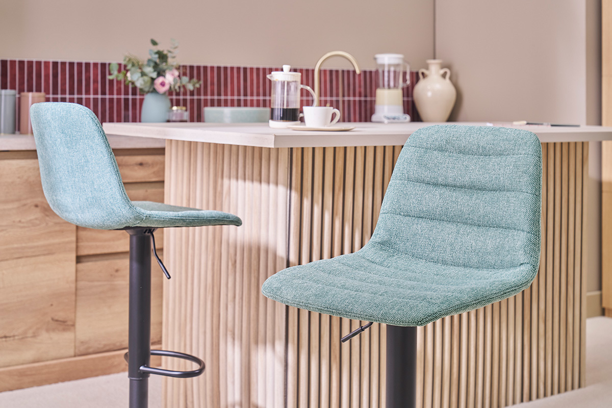 Dos taburetes de bar de tela celad�n frente a un mostrador de madera.