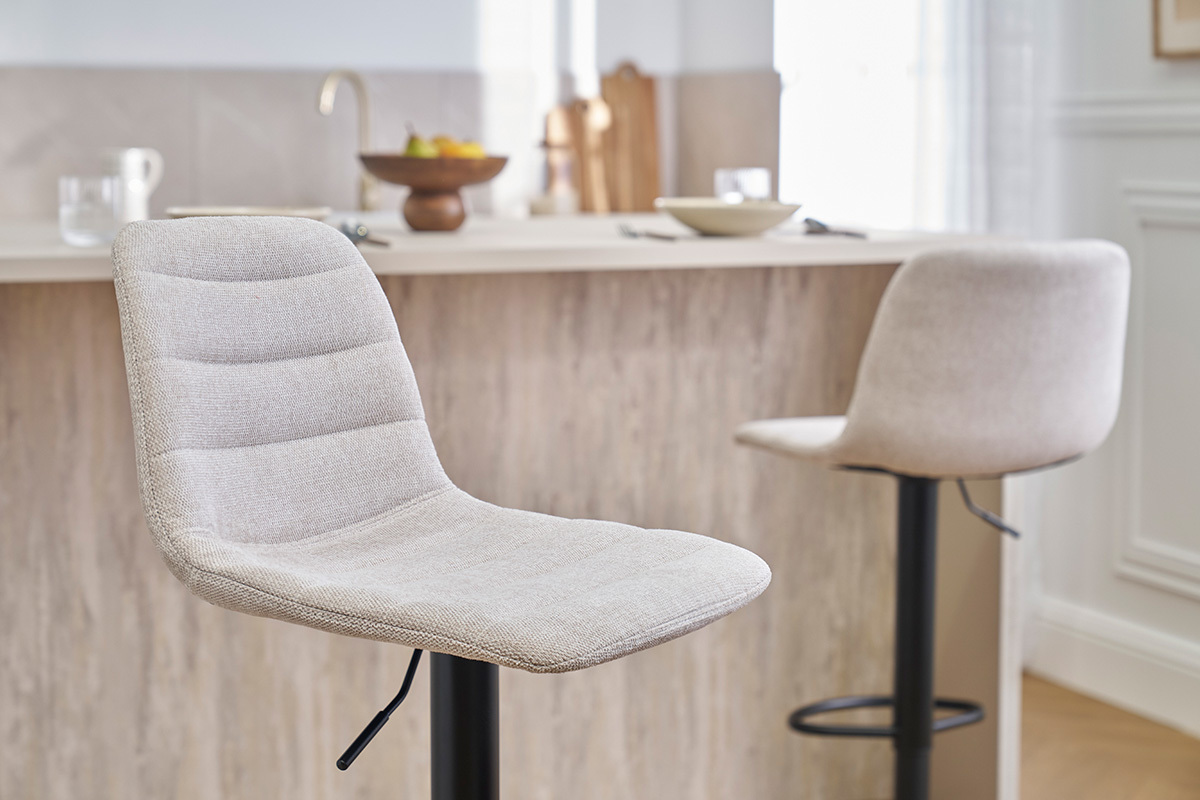 Taburetes de bar ajustables de tela beige y metal negro frente a un mostrador.