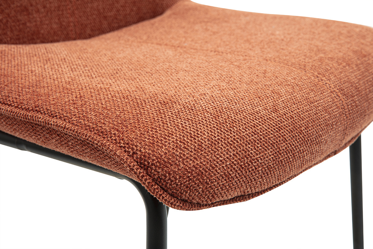 Primer plano de un taburete de tela color tierra quemada con patas de metal negro.