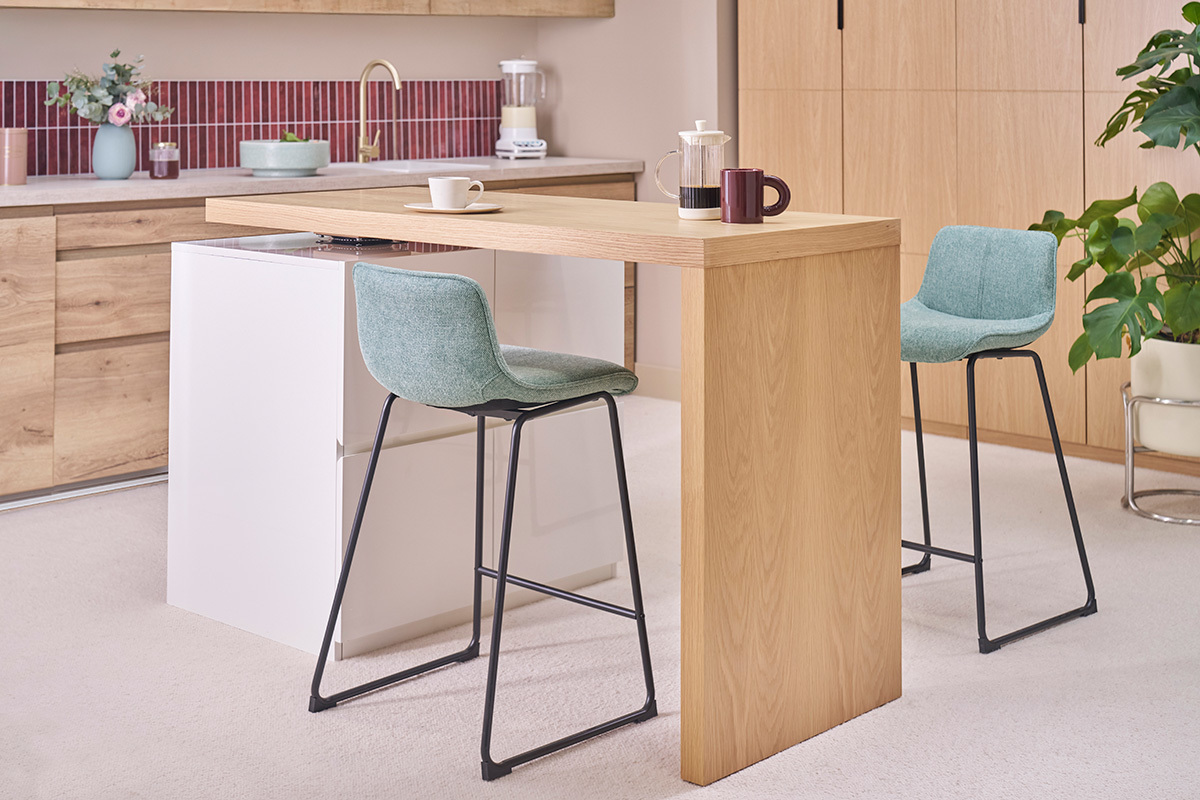 Taburetes de bar de tela azul-verde con patas de metal negro, en una cocina moderna.