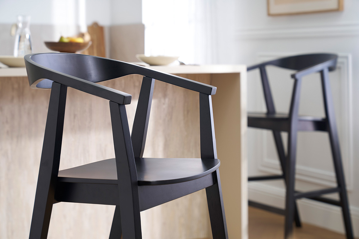 Dos taburetes de bar negros de madera BAHIA cerca de un mostrador, vista ampliada.