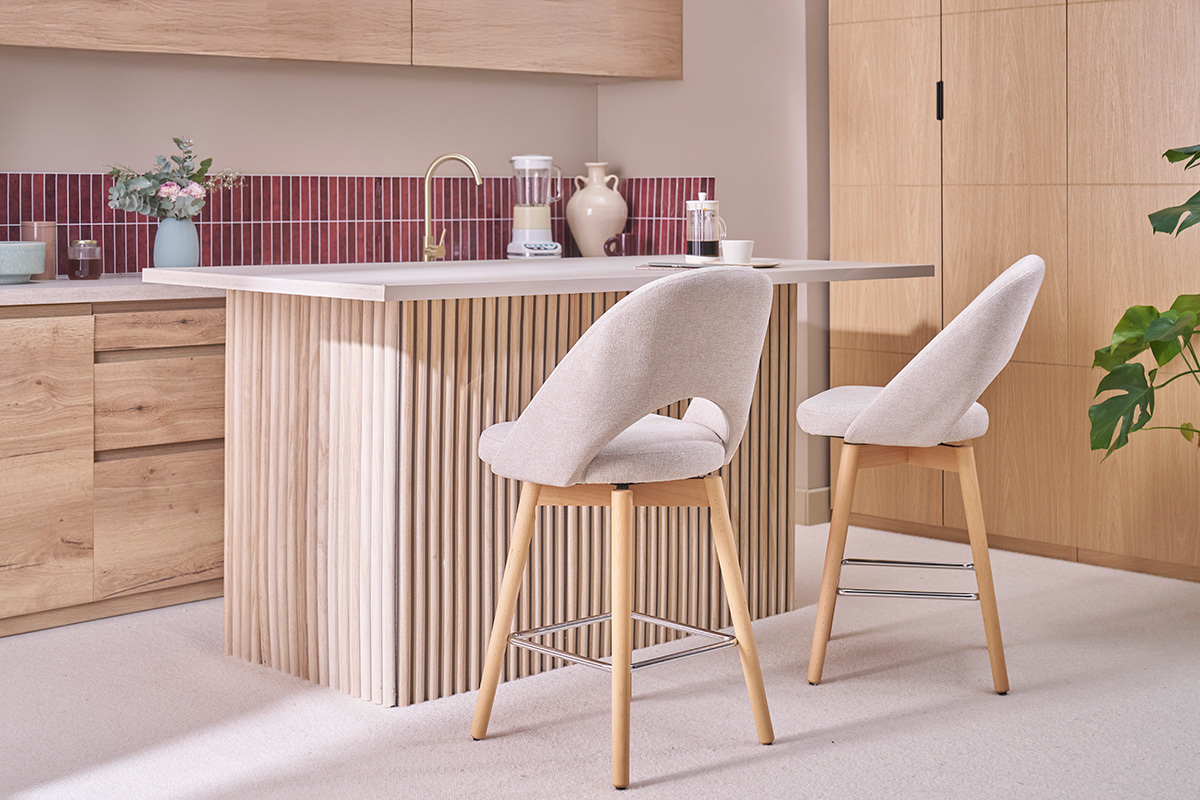 Dos taburetes de bar modernos de tela con patas de madera, colocados frente a un mostrador de cocina.
