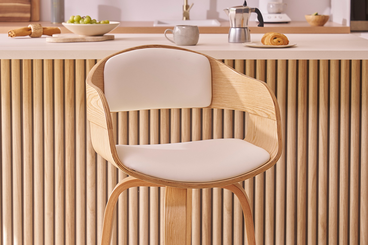 Taburete de bar escandinavo de madera clara con asiento de poliuretano blanco frente a una encimera de cocina.