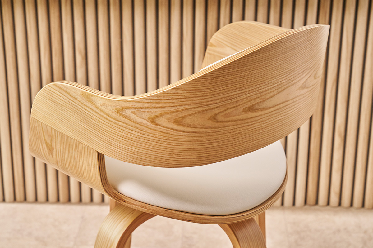 Respaldo y asiento de un taburete de bar escandinavo de madera clara y cuero sint�tico blanco, vista lateral.
