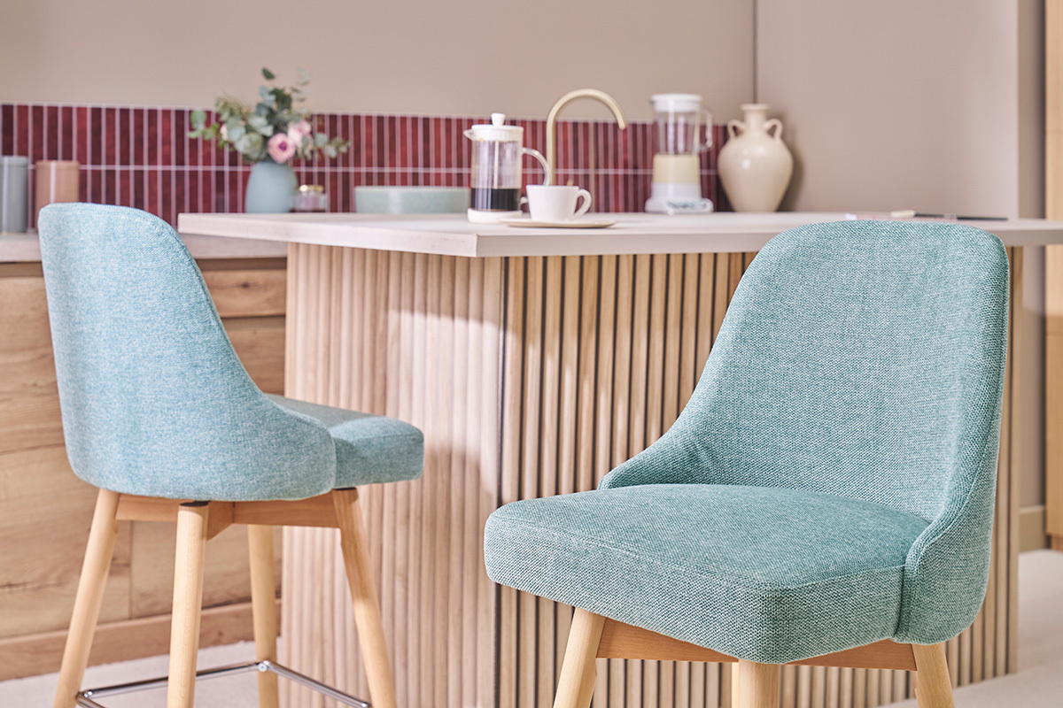 Taburetes de bar verdes celad�n en tela y madera, frente a un mostrador moderno.