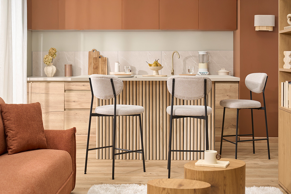 Taburetes de bar BEKA en tela beige y metal negro frente a isla, interior moderno.