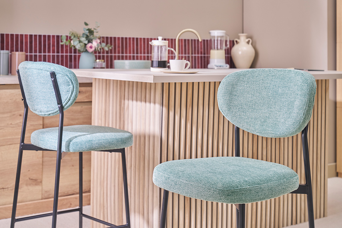Dos taburetes de bar de tela celad�n y metal negro frente a una isla de cocina.
