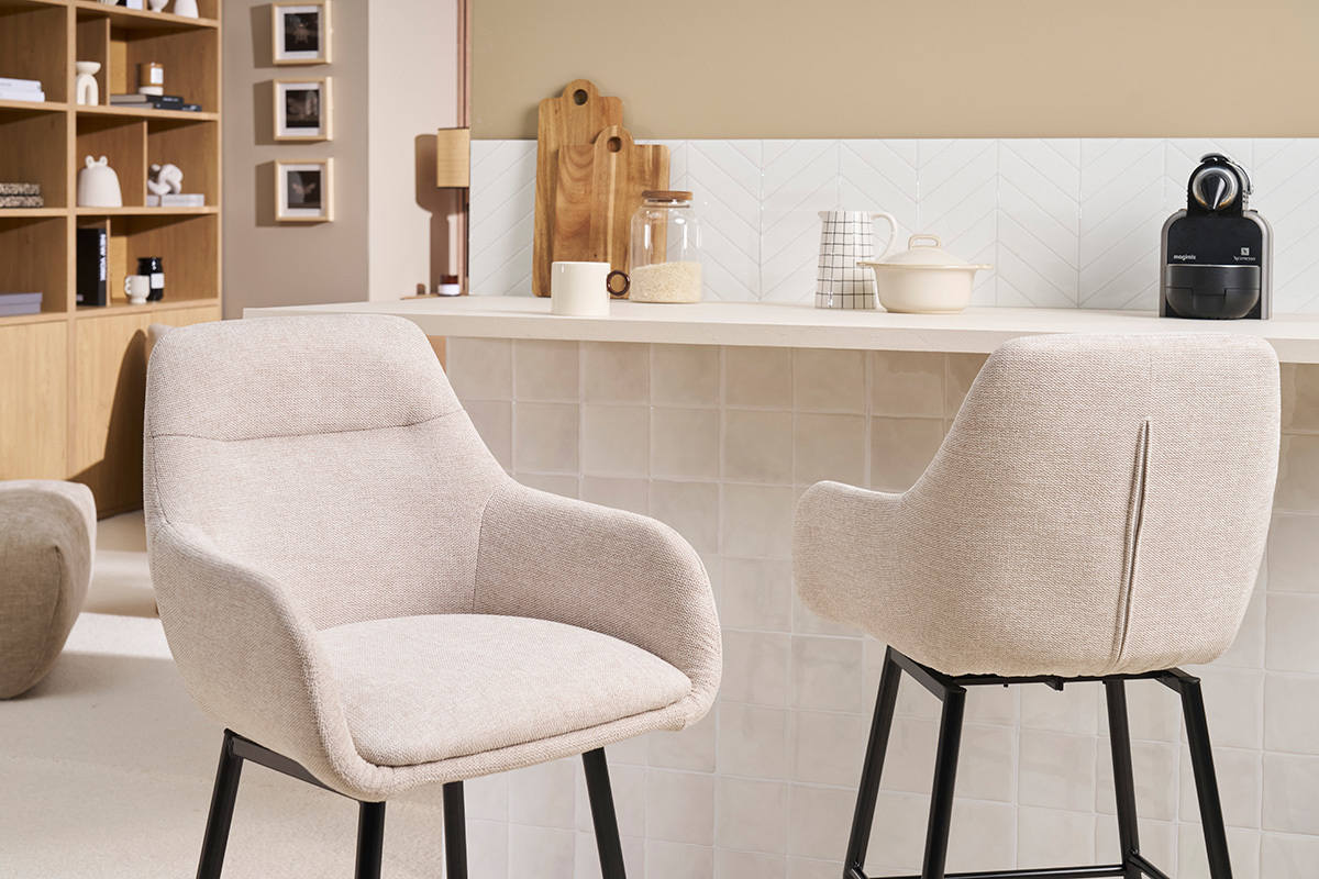 Taburetes de barra de tela beige y metal negro frente a un mostrador en una cocina.