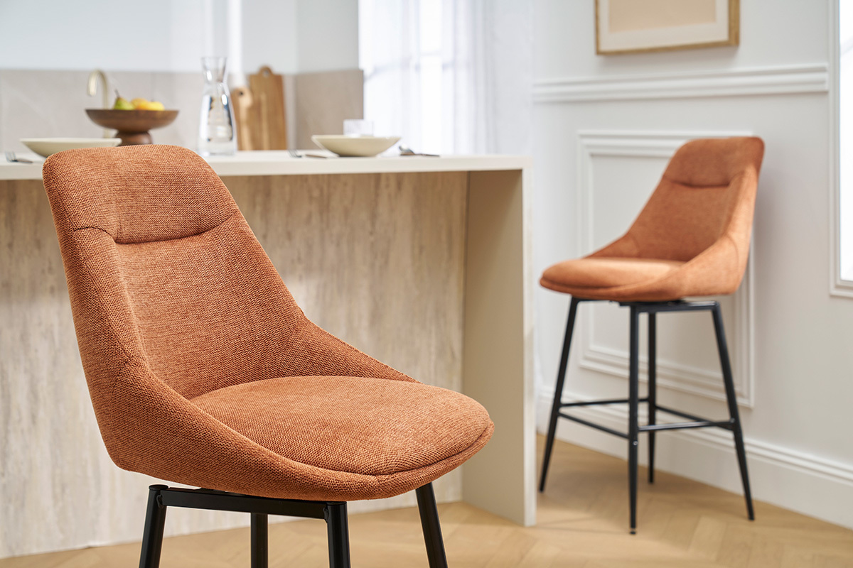 Dos taburetes de bar de tela color tierra quemada y patas de metal, en una cocina moderna.