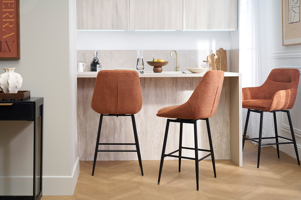 Tres taburetes de bar ALESS en tela tierra quemada y metal alrededor de una encimera de cocina.