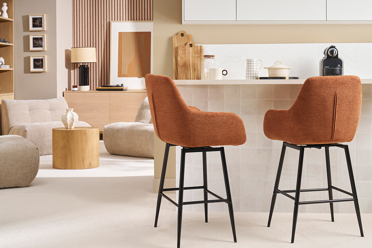 Dos taburetes de bar en tela color tierra quemada y metal negro frente a un mostrador.